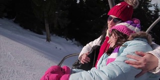 母亲和女儿在寒假乘坐滑雪缆车