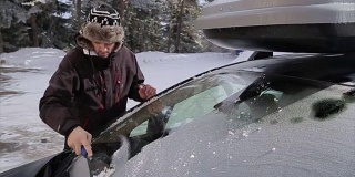 年轻人正在清理雪地里的汽车