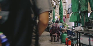 电影中，一名年长女子和一名年轻男子坐在市场里。