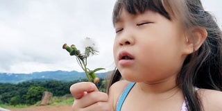 小女孩吹着雏菊花