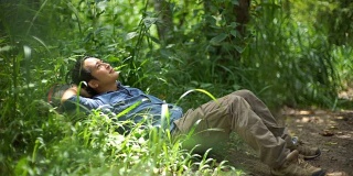 一个背着背包的男人躺在森林里睡觉和休息