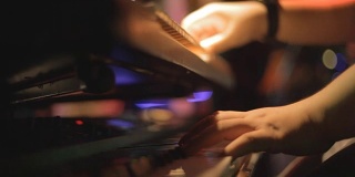 在夜总会弹奏钢琴键盘的手。