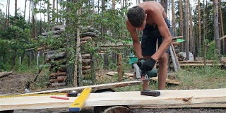 建筑工用圆锯切割木板。