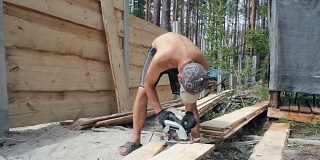 建筑工用圆锯切割木板。