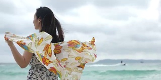 年轻快乐的女人戴着围巾在海滩上，慢镜头