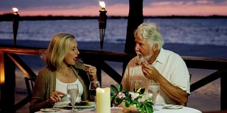 相爱的老年白种夫妇享受浪漫的海滨餐厅