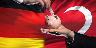 德国在土耳其投资，手把钱放在存钱罐里的旗帜背景