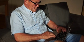 一位老人在家用互联网和笔记本电脑支付账单。网上银行，网上银行