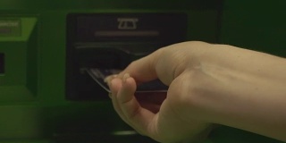 女士将塑料卡插入自动取款机。