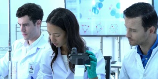 科学家们正在通过显微镜与在现代实验室或医学中心工作的同事们一起观察。科学的理念，测试发展和实验室产业。