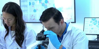 科学家们正在通过显微镜与在现代实验室或医学中心工作的同事们一起观察。科学的理念，测试发展和实验室产业。
