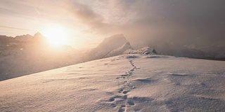 时间流逝的雪山与足迹在雪在日出早晨