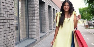 漂亮的年轻女孩穿着黄色的裙子，购物后心情好。慢动作