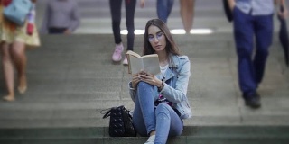 一个年轻女子坐在地铁的楼梯上看书