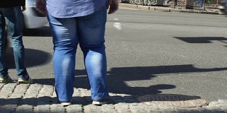 肥胖男性站立城市街道，久坐的生活方式影响，营养不良