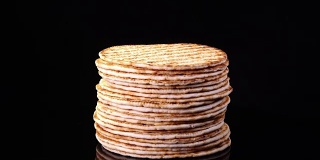 传统美味的扁面包(面饼、皮塔饼、薄饼、烤饼)在黑色背景下旋转