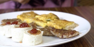 亚洲女人在酒店吃早餐。包括三文鱼煎蛋卷，汉堡，牙线，吐司，番茄酱。