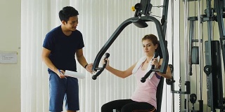 年轻的健身女士在健身房用负重器械做运动，健身训练理念