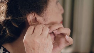 亚洲资深女性正在戴耳环和化妆视频素材模板下载