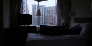 快乐女子在床上打旋跳跃，窗外香港全景