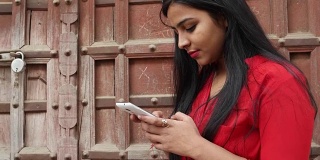 印度拉贾斯坦邦一名年轻女子手持手机微笑，用手机发短信打电话