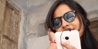 印度拉贾斯坦邦一名年轻女子手持手机微笑，用手机发短信打电话