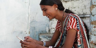 年轻的女士有美丽的脸在手机上，方便的智能联系方式，通知类型，信息交谈，说话，通信设备，无线网络信号，微笑，笑近距离在拉贾斯坦邦