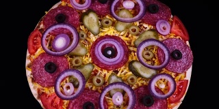 自制披萨，配有泡菜、意大利腊肠、橄榄、奶酪、新鲜番茄和洋葱圈