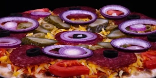 特写自制披萨与泡菜和新鲜洋葱旋转在黑色背景