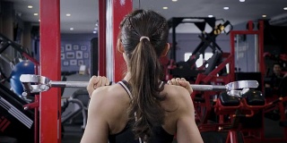年轻的健身女士在健身房用负重器械做运动，健身训练理念