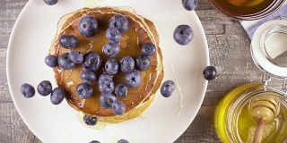 慢镜头煎饼早餐，浆果和蜂蜜俯视图