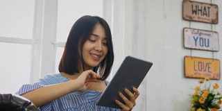 年轻的亚洲美女在家里使用数码平板电脑
