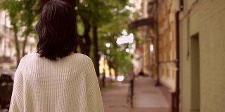 一个女性在城市街道上行走的后视图