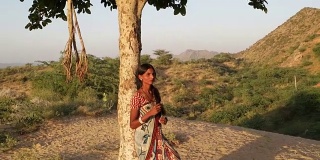 美丽的印度女士在树下等待爱人沉思，担心，想与蕨类在手里孵育烦躁不安，紧张秘密的聚会点日期户外夏天炎热的太阳阳光自然手持