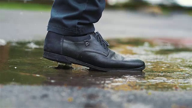 穿着黑鞋的男人慢镜头踩进水坑里