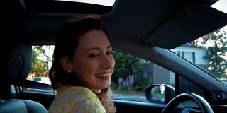 年轻女子开车和快速微笑