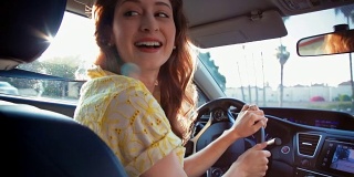 年轻女子开车微笑着坐在后座