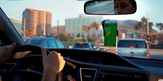一名年轻女子在停车时拿着绿屏手机