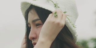 泰国美丽的女人戴着白色的帽子与花在花园里的特写