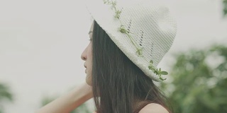 泰国美丽的女人戴着白色的帽子与花在花园里的特写
