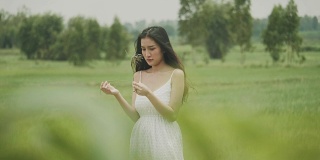 泰国美丽的女人背着草，而微笑和快乐与绿色的农场区域