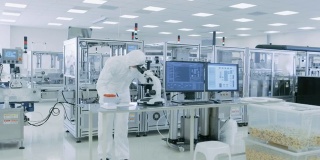 在无菌高精密制造实验室里，科学家们穿着防护服使用计算机和显微镜，做制药、生物技术和半导体研究。