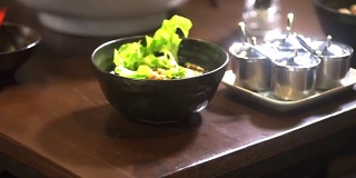 在餐馆里，服务员用黑色的碗端汤面。