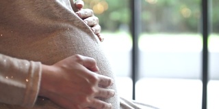孕妇轻轻抚摸着肚子，怀孕/分娩