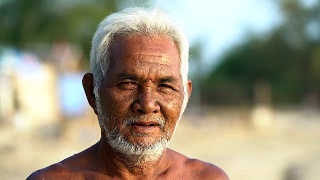 一位亚洲老人看着照相机的肖像。视频素材模板下载