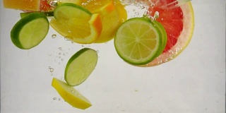 几片柠檬、柠檬、橙子、葡萄柚等柑橘类水果落入水中，溅起水花和气泡，这是慢镜头特写
