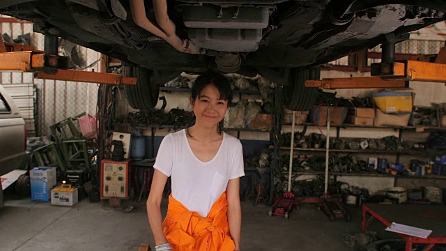 一个年轻美丽的汽车技师在汽车车间的肖像，在后台服务。汽车服务理念。多莉拍摄