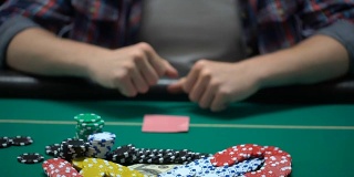 扑克玩家检查自己的牌，把美元放在桌上，全押