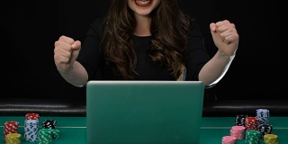 女人在笔记本电脑上玩游戏，显示成功的姿态，赢得赌注，财富