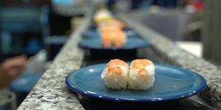 寿司和生鱼片。寿司和生鱼片在传送带上滚动。日本传统的生活方式。